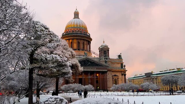 St. Petersburg, Russia - November 23, 2025: View of the snow-covered St. Isaac's Square with snow-covered trees and St. Isaac's Cathedral on a winter day at sunset. 4K