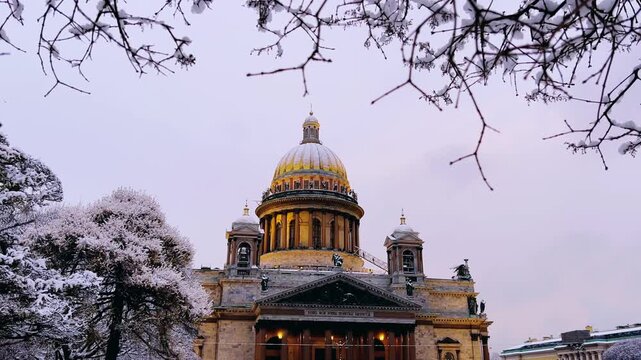 St. Petersburg, Russia - November 23, 2025: View of the snow-covered St. Isaac's Square with snow-covered trees and St. Isaac's Cathedral on a winter day at sunset. 4K