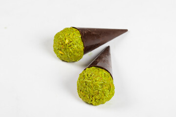 Modern Dubai chocolate dessert. Dark chocolate cone with a ball of crispy kataifi dough with pistachio paste. White background. Close-up.