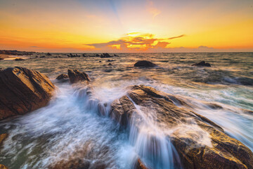 Fototapeta premium sunset over the sea, with waves over the rock like a waterfall 