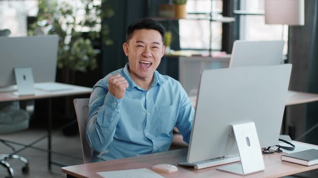 A young man sits at a desk in a contemporary office, focused on his computer screen while typing. Sunlight illuminates the workspace filled with plants and simple decor. - Powered by Adobe