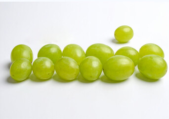 Obraz premium Doce uvas verdes frescas alineadas sobre fondo blanco, símbolo tradicional de la Nochevieja española, ritual de fin de año para atraer la buena suerte y celebrar el Año Nuevo