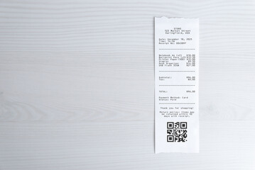 Paper receipt with qr code on white desk, expense documentation concept with copy space for digital payment, accounting, auditing, and expense management applications