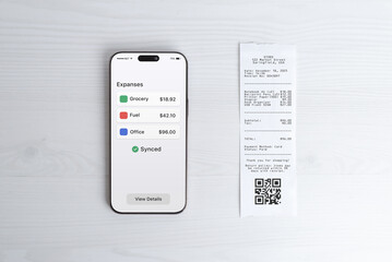 Smartphone displaying expense overview dashboard next to paper receipt, modern bookkeeping and finance app concept for business reporting, analytics, and digital expense tracking
