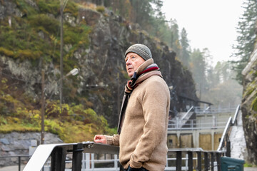 Independence in later life is shown in a man over seventy standing confidently outdoors, dressed for cold weather, representing self-sufficiency, freedom of movement, and personal strength beyond reti