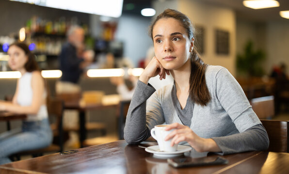 Pretty girl drinks coffee in a cafe interior