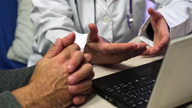 Medical professional gesturing with hands while talking to an elderly patient during a consultation. A physician giving bad news in the office