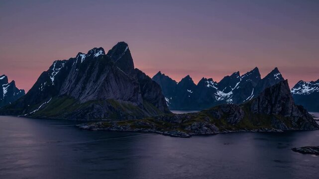 Snow-capped mountains rise majestically over tranquil waters, reflecting the brilliant colors of the sunset. A serene lake mirrors the vibrant hues, creating a stunning natural sce