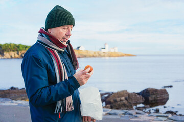 Simple living concept with an older man holding basic food outdoors, highlighting modest lifestyle, independence, self care, everyday routine, and quiet moments in old age.