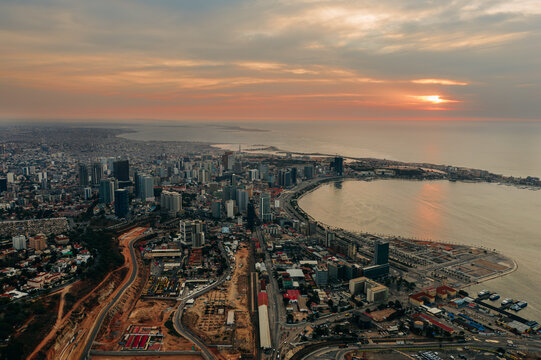 Wide aerial view of Luanda skyline at sunset, vibrant African coastal city meeting the Atlantic Ocean, Angola