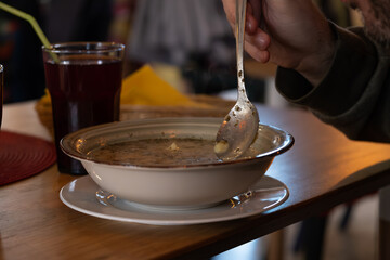 Person eating soup with spoon at cafe table