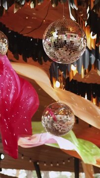 Vertical video. Disco balls hanging between colorful fabrics. Decor for a party or wedding, disco party.
