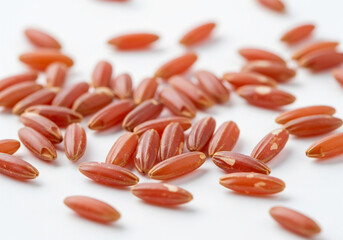 Scattered raw red rice grains on white background, healthy organic food