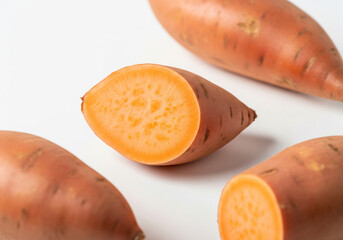 Fresh sweet potato cut in half showing orange flesh isolated on white background