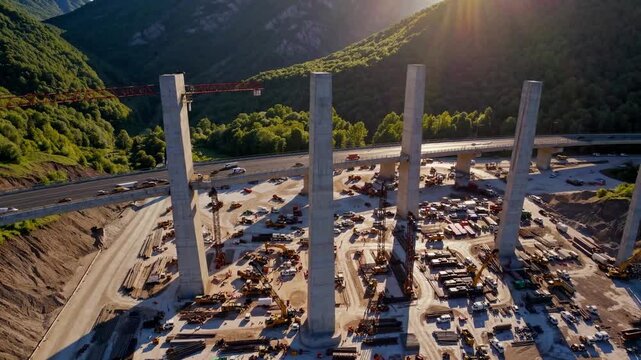 A towering bridge under construction spans across a lush valley, supported by multiple concrete pillars. Heavy machinery works diligently, creating a busy scene of progress and eng