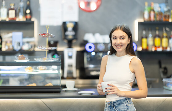 Pretty woman drinks coffee in a cafe interior