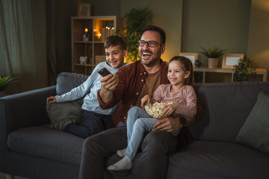 Father and children watching movie on tv at home