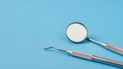 Dental tools including a mirror and explorer on a vibrant blue background, showcasing essential instruments for oral health and hygiene practices in a clinical setting