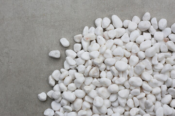 Smooth, white, polished pebbles scattered on a dark black surface.