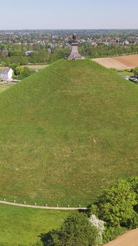complete monument parking town buildings accented by green grass trees open fields lion's mound waterloo belgium to left right circling drone shot view leeuw van 