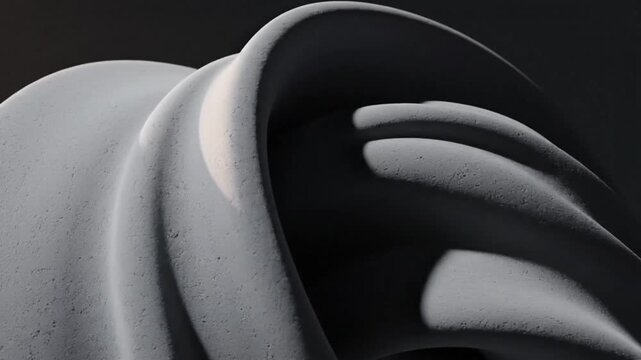 Close-up of a smooth, curved gray object with a wavy surface against a dark background with shadows.