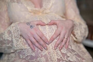 mains d'une femme enceinte sur son ventre rond avec une robe de dentelle