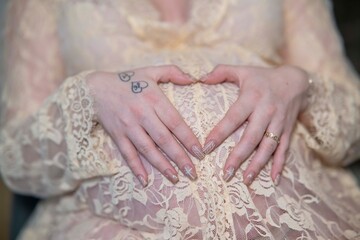 mains d'une femme enceinte sur son ventre rond avec une robe de dentelle