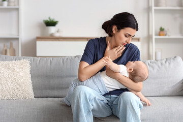 Obraz premium Young mother suffering from postnatal depression with her baby on sofa at home