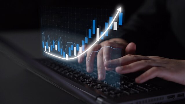 Close-up of a person using a laptop while an animated financial graph with upward trends appears. Represents data analysis and economic growth in a modern business environment. Copula - Powered by Adobe