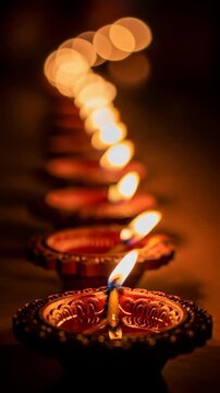 Row of traditional Indian clay diya lamps glowing for Diwali festival celebration. Abstract religious light. Vertical video