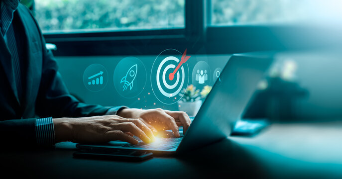 Business goal and digital strategy success concept with businessman typing on laptop computer and futuristic target icon surrounded by growth chart, rocket launch, teamwork innovation for achievement