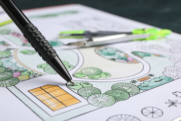 Pen with zoning plan on dark background, closeup