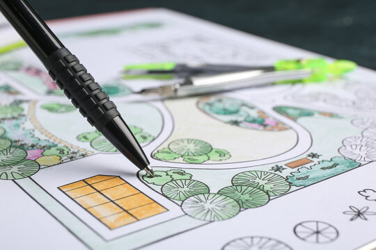 Pen with zoning plan on dark background, closeup