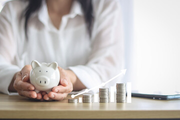 women hand holding coin in to white piggy bank for use to business and money concept