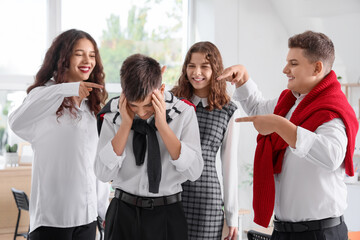 Obraz premium Classmates bullying teenage boy in classroom