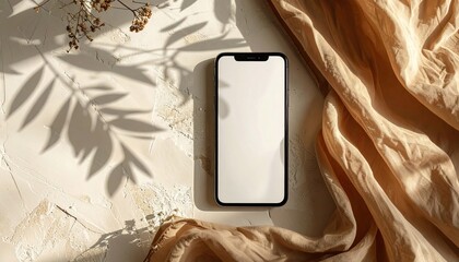 A smartphone rests on a textured surface beside draped fabric, with floral shadows cast upon it