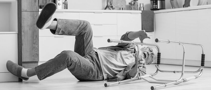 Senior man with walker falling on floor in kitchen