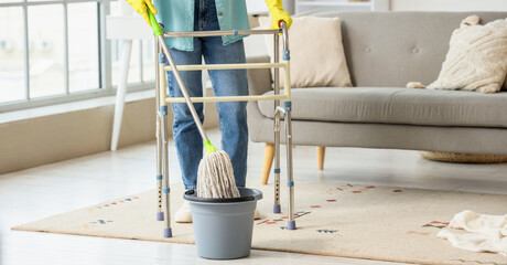 Mature woman with walker mopping floor at home