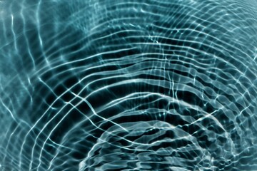 Blue water with ripples on the surface. Defocus blurred transparent blue colored clear calm water surface texture with splashes and bubbles. Water waves with shining pattern texture background.
