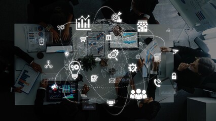 A high-angle view of a business meeting featuring a diverse team discussing strategies with digital graphics overlay, encapsulating technology and data insights. Raster