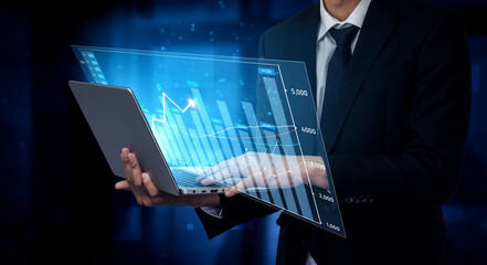 A business professional interacts with a futuristic laptop featuring holographic data visualization, highlighting financial trends and market analysis in a modern office environment. Scalp