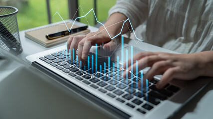 A close-up of hands typing on a laptop keyboard with overlaid digital graphs and data elements, representing modern business analysis and financial insights. Scalp