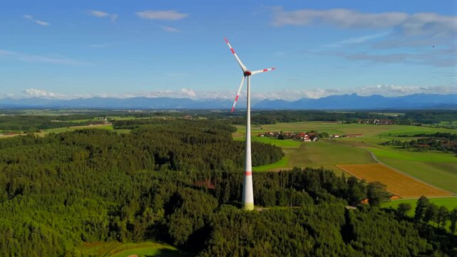 Aerial view of wind turbine in Bavaria, Ebersberg region, Germany. Luftaufnahme einer Windturbine vor dem Hintergrund der Alpen in Bayern, Deutschland. Wind turbine on golf course overlooking alps. 