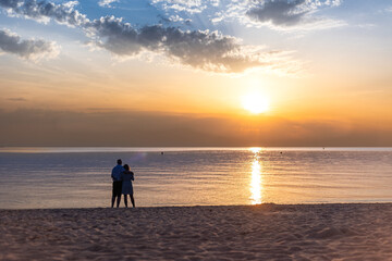 A couple on the sand sea beach enjoying the sunset