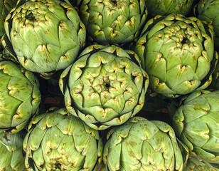 Overhead shot of a pile of freshly picked artichokes, showcasing their intricate, layered green petals. Focus is on texture