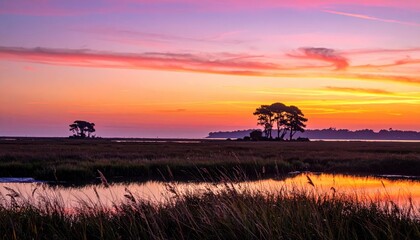 Dramatic sunset sky with colorful clouds over salt marsh landscape with winding river and tall grass. Nature concept