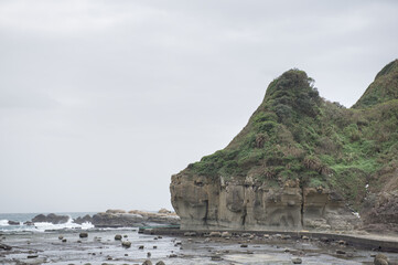 Scenic view of rhinoceros rock and lush green hills along the rugged coastline of Heping Island Park, Keelung, Taiwan.