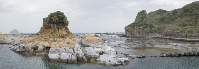 A stunning cinematic panoramic view of the "Guardian Rock" and unique eroded sphinx or lion shaped rock sandstone formations along the coastline in Heping Island Park, Keelung, Taiwan.