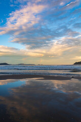 reflexo do céu e o pôr-do-sol na Praia Palmas do Arvoredo cidade de Governador Celso Ramos Santa Catarina Brasil região da Grande Florianopolis ao fundo um arco-íris na costa de Bombinhas Mariscal