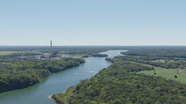 Wide aerial panorama of river valley with distant power plant and surrounding forested landscape